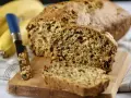 Pyszny chlebek bananowy, świeżo upieczony, z widocznym nożem i bananami w tle. Idealny na śniadanie.