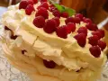 Puszysty, wielowarstwowy tort bezowy z bitą śmietaną i malinami. Wygląda jak najpyszniejszy tort bezowy, jaki można sobie wyobrazić!