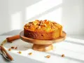 Pomarańczowe, zdrowe ciasto z orzechami i plasterkami pomarańczy na drewnianej podstawce. Obok leży marchewka i nóż.