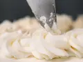 Dekorowanie tortu puszystym kremem bananowym za pomocą rękawa cukierniczego.