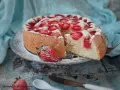 Puszysty biszkopt z truskawkami, posypany cukrem pudrem, kusi apetycznym wyglądem. Idealny na letnie popołudnie.