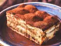 Pyszne tiramisu bez pieczenia, posypane obficie kakao, na niebieskim talerzu. Idealne na deser.