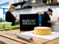 Idealny biszkopt maślany, gotowy do dekoracji. Obok trzepaczka i czarna tabliczka z napisem "BISZKOPT IDEALOY".