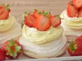 Mini torty pavlova z bitą śmietaną i świeżymi truskawkami.