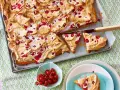 Pyszne ciasto z porzeczkami i pianką, pokrojone na kawałki, czeka na talerzu. Obok miseczka świeżych porzeczek.