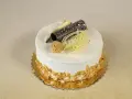 Elegancki tort rafaello z wiórkami migdałowymi, czekoladową rurką i dekoracjami z białej czekolady.