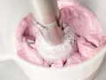 Ania gotuje pyszny krem jogurtowy z owocami leśnymi. Blender miesza różową masę, tworząc piankę.