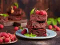 Stos pysznych brownie z malinami, ozdobiony świeżymi malinami i listkami mięty.