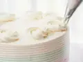 Dekorowanie tortu kremem miętowym do tortu. Delikatne różyczki z kremu zdobią wierzch ciasta.