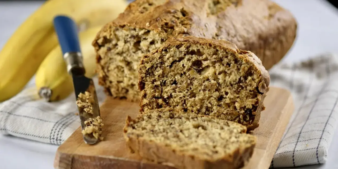 Pyszny chlebek bananowy, świeżo upieczony, z widocznym nożem i bananami w tle. Idealny na śniadanie.