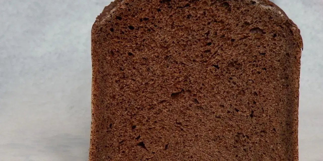 Kawałek ciemnego, puszystego chleba czekoladowego z widocznymi porami. Idealny na słodkie śniadanie.