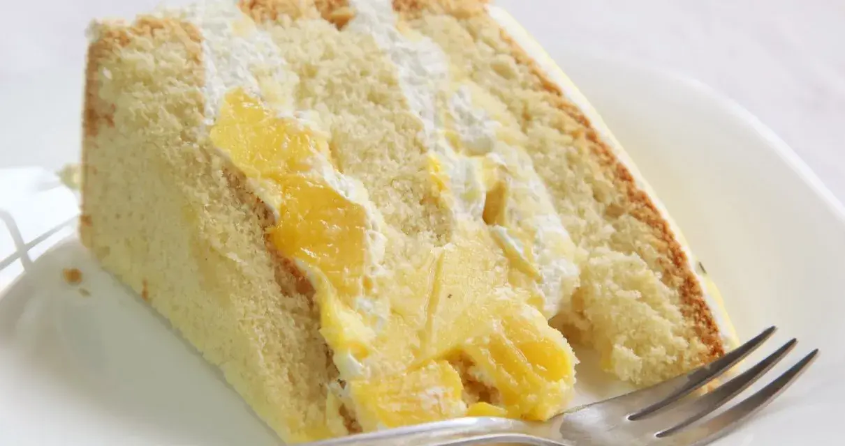 Puszysty biszkopt przełożony kremem i kawałkami mango. Ten tort mango wygląda pysznie!