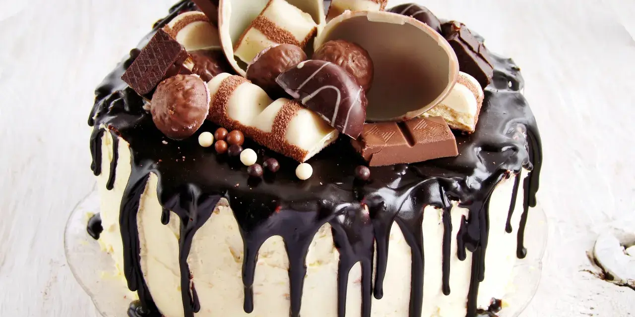 Wyjątkowy tort kinder bueno, oblany czekoladą, ozdobiony pralinkami i kawałkami batoników.