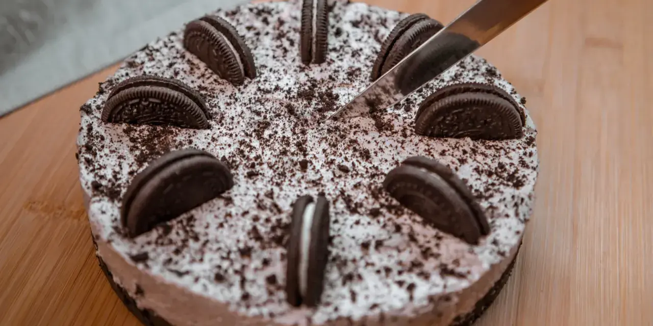 Nóż kroi pyszny tort oreo, ozdobiony ciasteczkami i posypką.