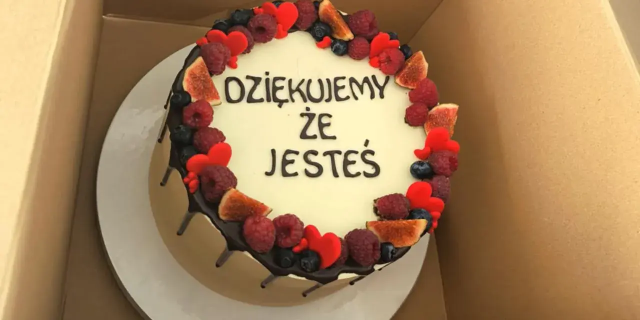 Ozdobiony owocami tort z napisem "Dziękujemy, że jesteś". Wskazówka, jak zrobić napis na torcie.