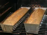 Dwa bochenki chleba dukana pieką się w piekarniku, w metalowych formach.