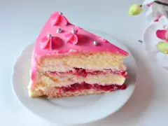 Pyszny tort malinowy z różowym lukrem i srebrnymi perełkami, przełożony kremem i malinową konfiturą.