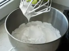 Ubita śmietana z mascarpone, idealne proporcje dla puszystego kremu. Mikser z białą masą w metalowej misie.