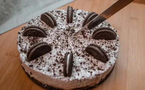 Nóż kroi pyszny tort oreo, ozdobiony ciasteczkami i posypką.