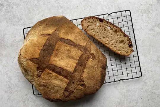 Chleb pszenno orkiszowy, świeżo upieczony, z chrupiącą skórką i puszystym wnętrzem, czeka na kromkę.