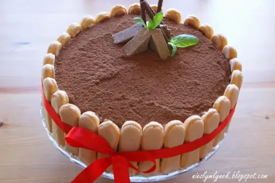 Elegancki tort whisky, udekorowany biszkoptami, kakao i miętą. Czerwona wstążka dodaje mu uroku.