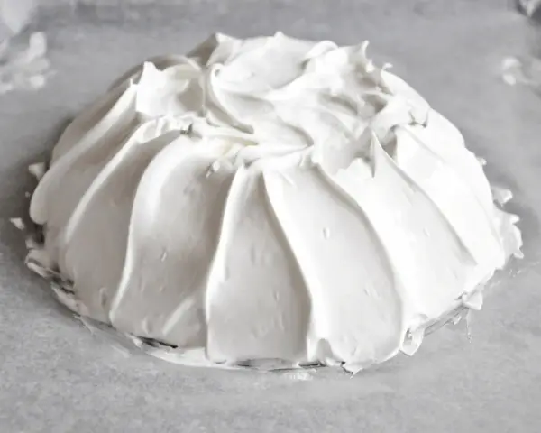 Idealna beza pavlova, która zawsze wychodzi, z puszystą pianką uformowaną na papierze do pieczenia.