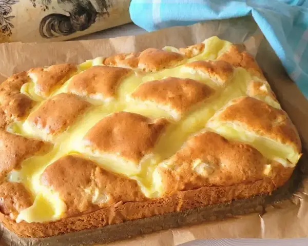 Puszyste ciasto jogurtowe z kremowym nadzieniem, upieczone na papierze do pieczenia.