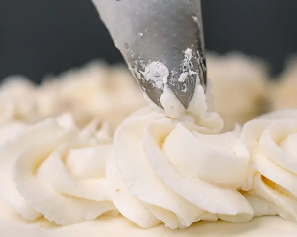 Dekorowanie tortu puszystym kremem bananowym za pomocą rękawa cukierniczego.