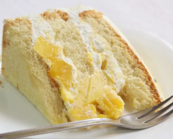 Puszysty biszkopt przełożony kremem i kawałkami mango. Ten tort mango wygląda pysznie!