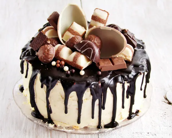 Wyjątkowy tort kinder bueno, oblany czekoladą, ozdobiony pralinkami i kawałkami batoników.