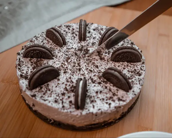 Nóż kroi pyszny tort oreo, ozdobiony ciasteczkami i posypką.