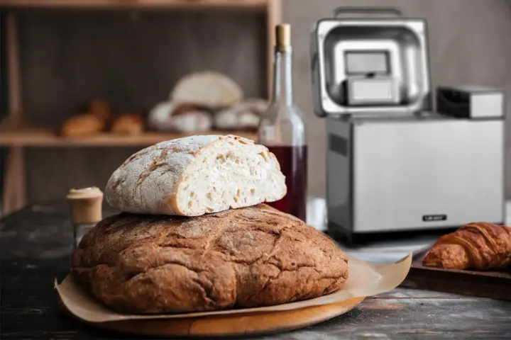 Chrupiący chleb z automatu, świeżo upieczony, czeka na śniadanie. Obok butelka wina i croissant.