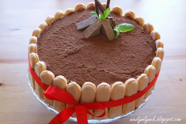 Elegancki tort whisky, udekorowany biszkoptami, kakao i miętą. Czerwona wstążka dodaje mu uroku.