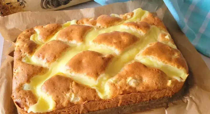 Puszyste ciasto jogurtowe z kremowym nadzieniem, upieczone na papierze do pieczenia.