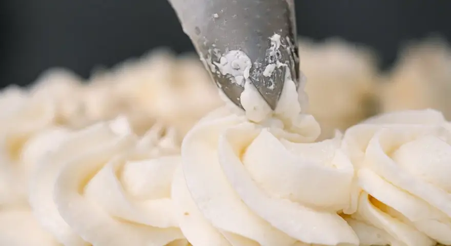 Dekorowanie tortu puszystym kremem bananowym za pomocą rękawa cukierniczego.