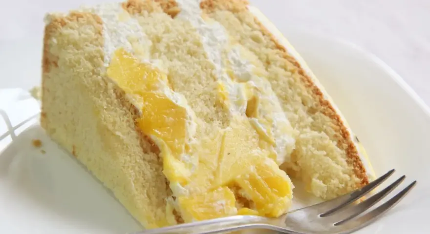 Puszysty biszkopt przełożony kremem i kawałkami mango. Ten tort mango wygląda pysznie!
