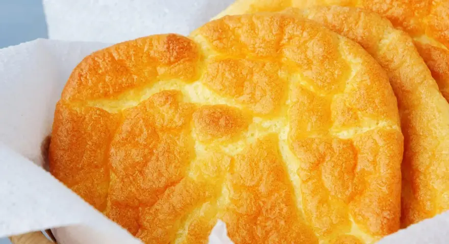 Puszyste, złociste **cloud bread** w koszyku wyłożonym papierem. Wyglądają jak chmurki!