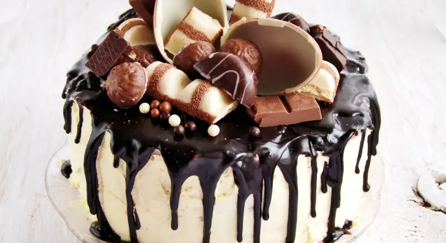 Wyjątkowy tort kinder bueno, oblany czekoladą, ozdobiony pralinkami i kawałkami batoników.