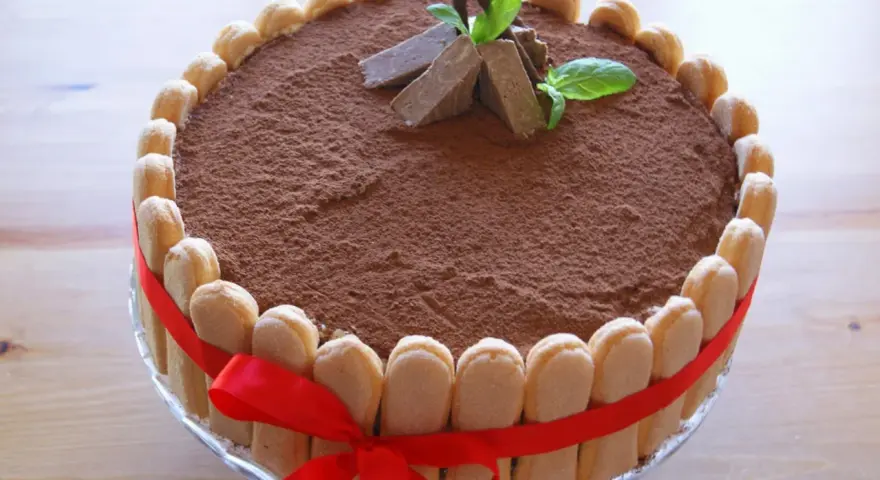 Elegancki tort whisky, udekorowany biszkoptami, kakao i miętą. Czerwona wstążka dodaje mu uroku.