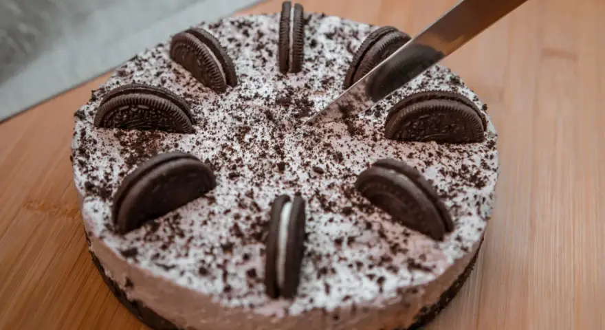 Nóż kroi pyszny tort oreo, ozdobiony ciasteczkami i posypką.