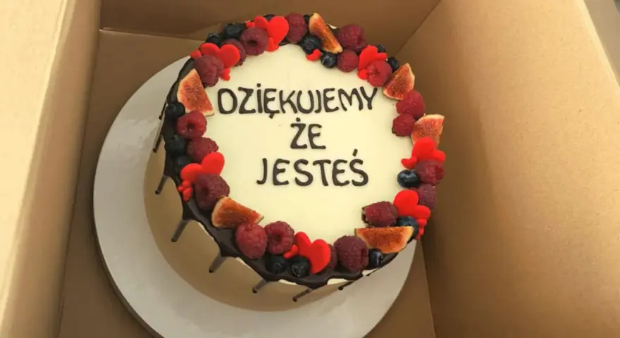 Ozdobiony owocami tort z napisem "Dziękujemy, że jesteś". Wskazówka, jak zrobić napis na torcie.