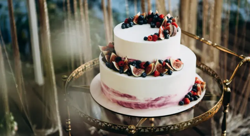 Elegancki tort piętrowy na 40 osób, ozdobiony świeżymi figami, borówkami i malinami. Idealny na wyjątkowe przyjęcie.