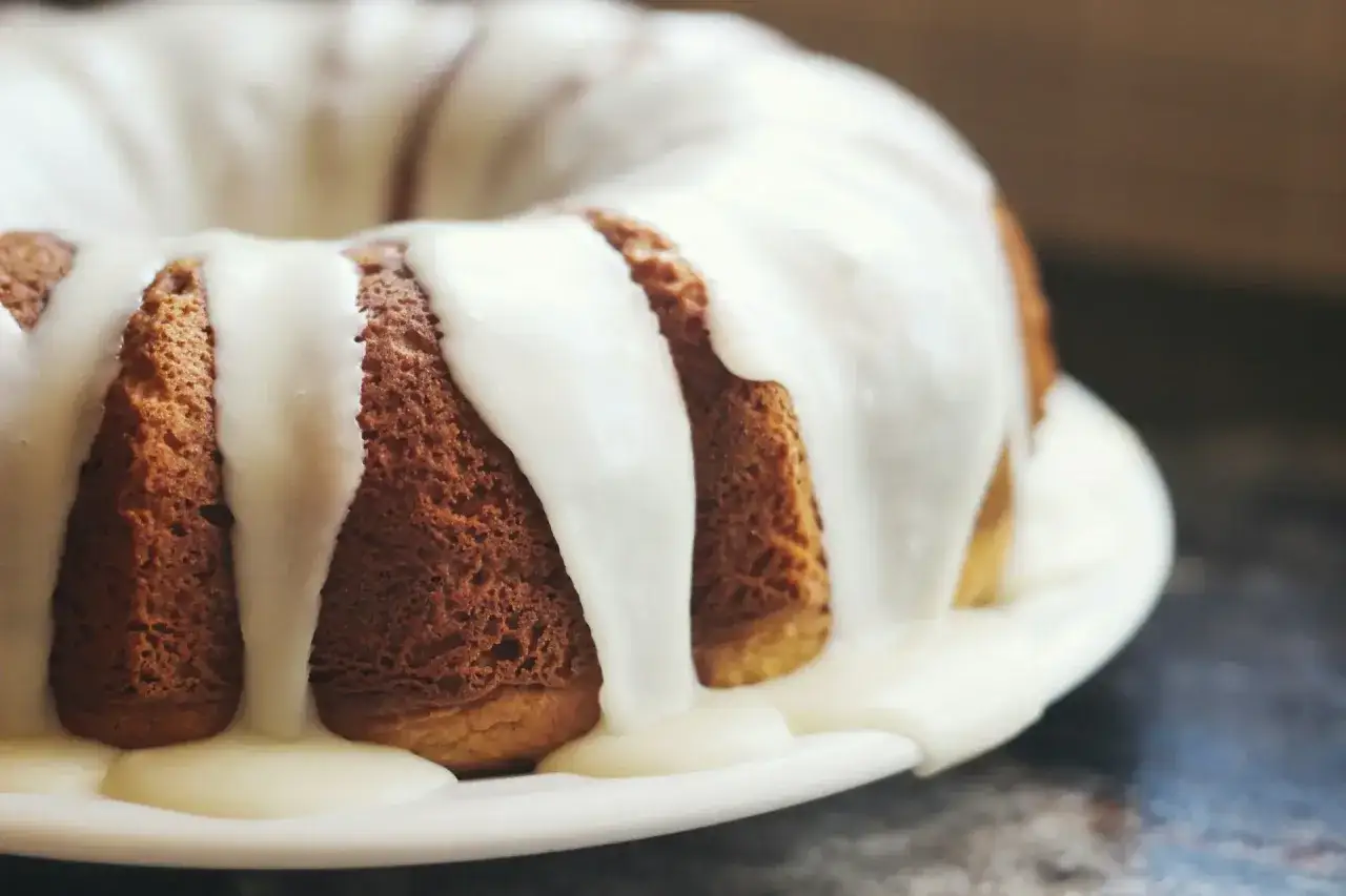 Puszysta babka z obfitym lukrem do babki, kt&oacute;ry spływa po jej bokach, tworząc apetyczny deser.
