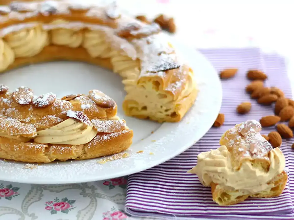 Pyszny paris brest, okrągłe ciasto ptysiowe z kremem i migdałami, posypane cukrem pudrem.