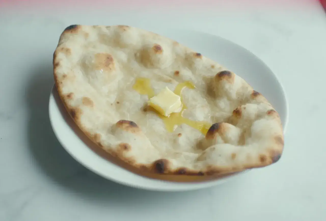 Puszysty, lekko przypieczony naan z rozpuszczającym się masłem. Idealny do indyjskich dań, jak roti.