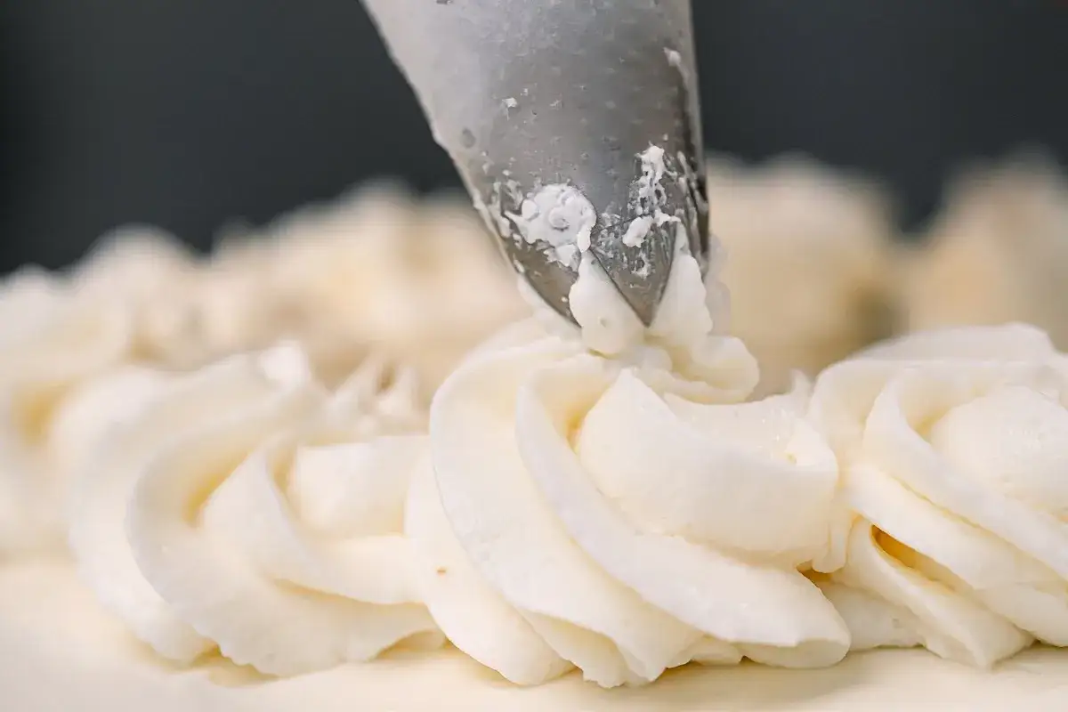 Dekorowanie tortu puszystym kremem bananowym za pomocą rękawa cukierniczego.